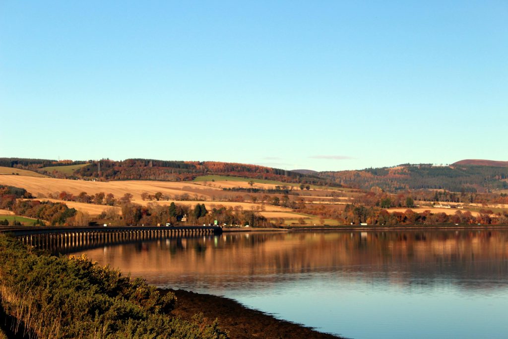 Serene autumn landscape with Cromarty Firth Bridge reflection, Scotland Highlands.