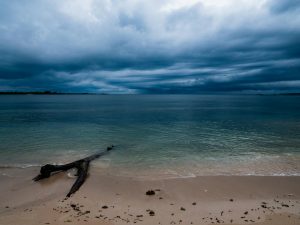 Stormy clouds loom over the serene beachscape of Kilwa Kisiwani, Tanzania.