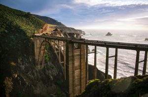 Stunning aerial view of Bixby Creek Bridge against the backdrop of Big Sur's dramatic coastline at sunset.