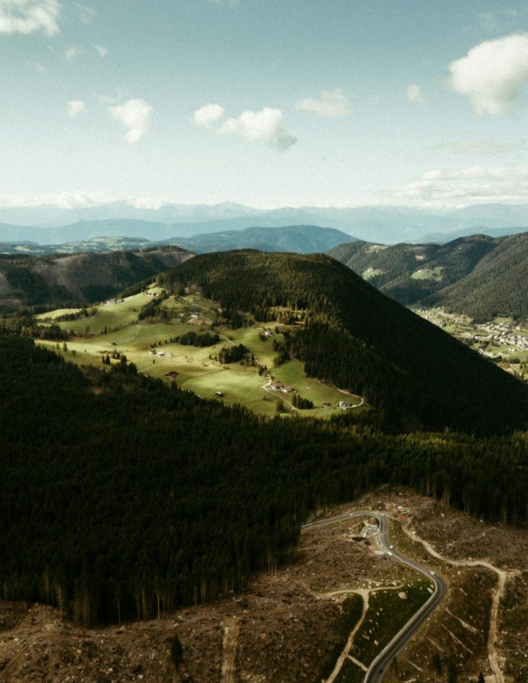 Stunning aerial view of Bolzano's lush mountainous landscape, showcasing vibrant greenery and winding roads.