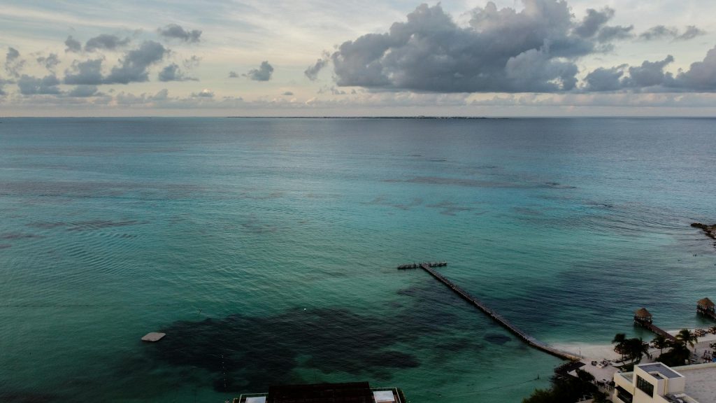 Stunning drone shot of the Caribbean Sea with a pier in Cancún, Mexico.