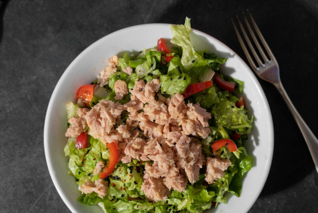 Top view of a fresh tuna salad with vibrant vegetables and a fork on the side.