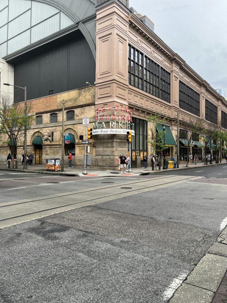 Urban scene of Reading Terminal Market in Philadelphia with pedestrians and historic buildings.