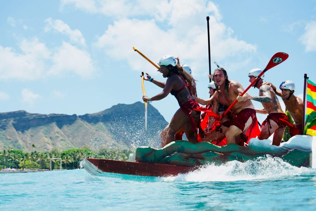 Vibrant scene of people paddling a canoe in Honolulu with Diamond Head in the background.