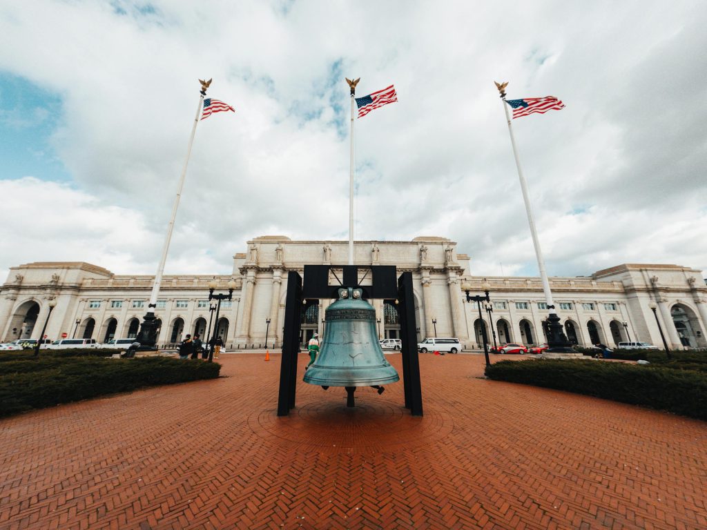Wide-angle view of Union Station with American flags and prominent bell in Washington DC.