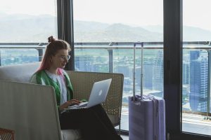 Woman working on a laptop in a hotel lounge with a stunning city view.
