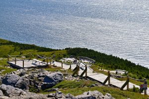Wooden boardwalk trails on a rocky hill with ocean view in Nova Scotia, Canada.
