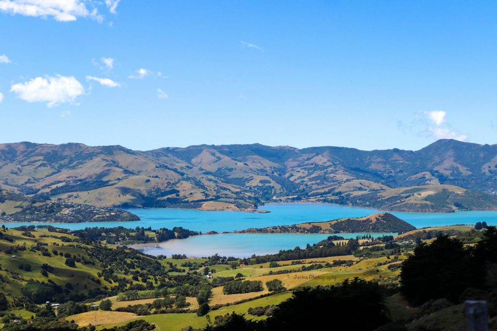 A stunning aerial view of Akaroa Harbor with lush green landscapes and surrounding hills in New Zealand.