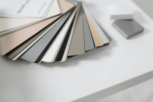 A variety of neutral color samples on a minimalist white desk for design purposes.