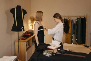 Fashion designer takes precise measurements of a client in a cozy studio setting.
