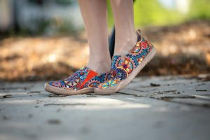 Vibrant casual shoes with colorful patterns worn outdoors on a sunny day.